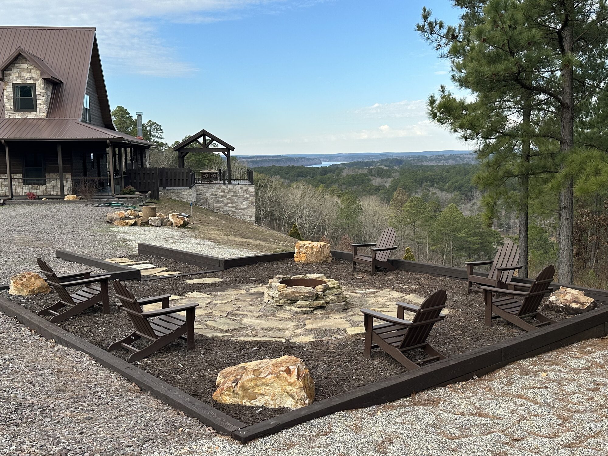 Fire pit and Adirondack chairs with a distant lake view